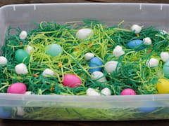 Easter-themed sensory bin with plastic eggs and Easter grass