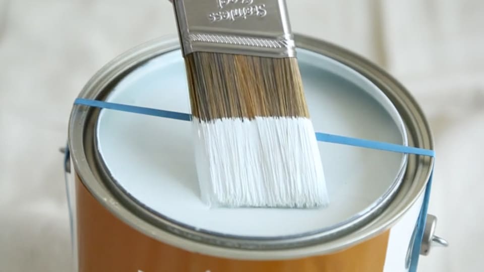 Wrap a rubberband around the paint can while painting